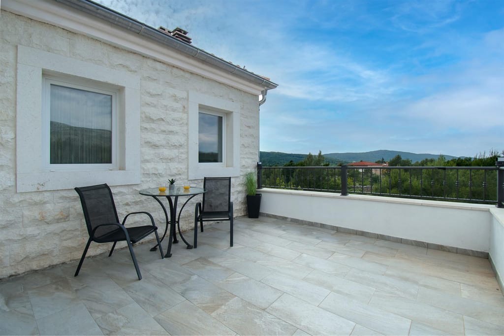 Balcony terrace with a table, two chairs and a view of the hills