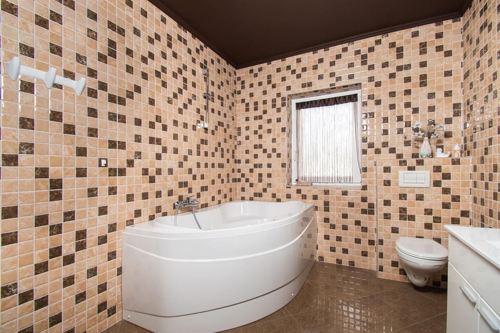 Bathroom with a corner bathtub and mosaic tiles