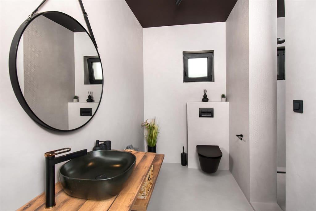 Modern bathroom with black fittings and a round mirror