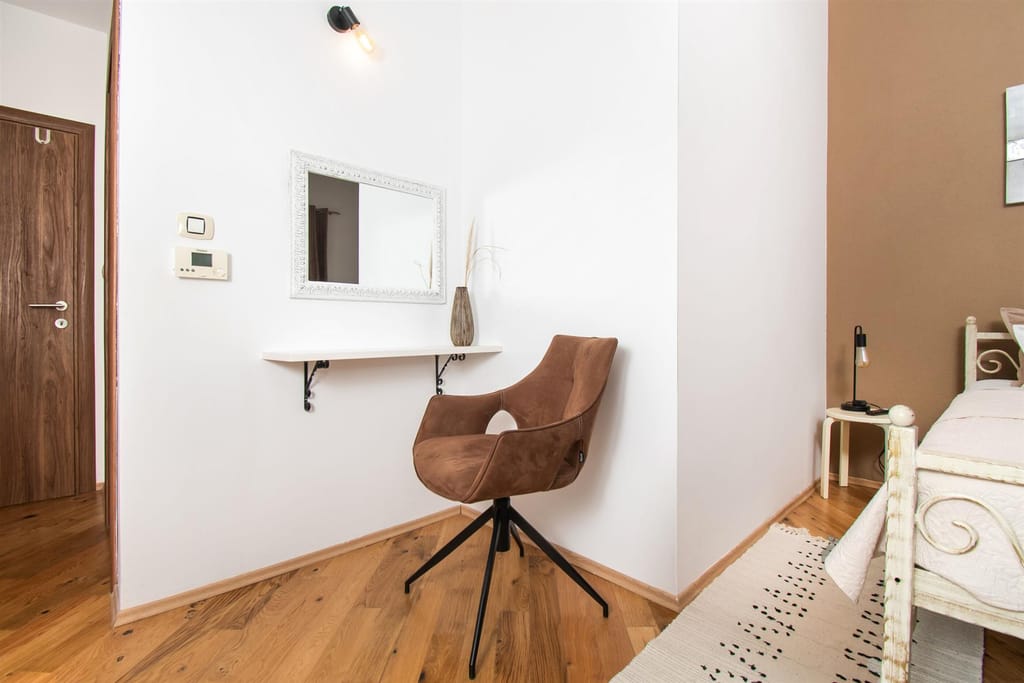 Bedroom vanity with a framed mirror and a suede chair