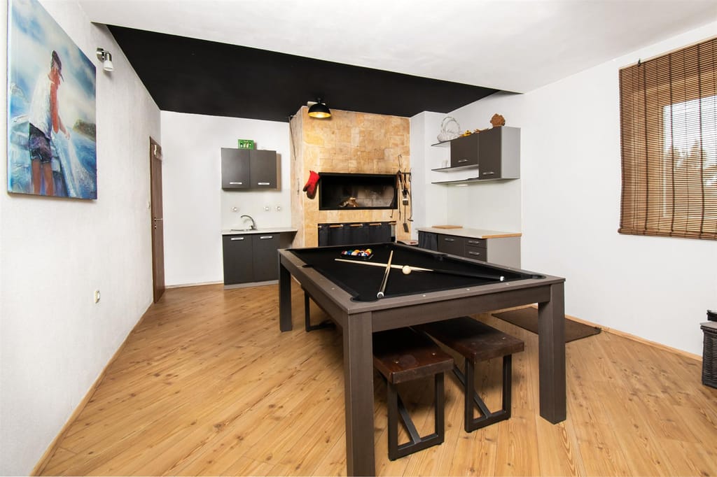 Billiard table in the games salon with the indoor grill behind it