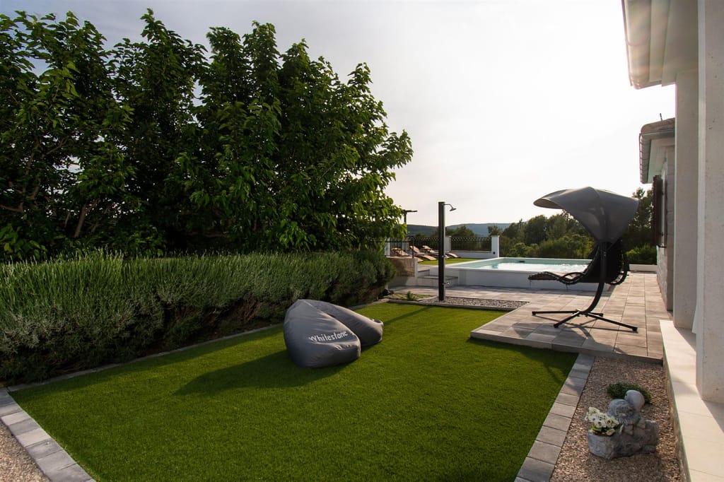 Lawn with bean bags and a hanging lounger, the pool beyond