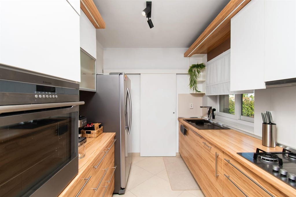 Fully equipped kitchen with wooden cabinets, a gas hob and a large fridge