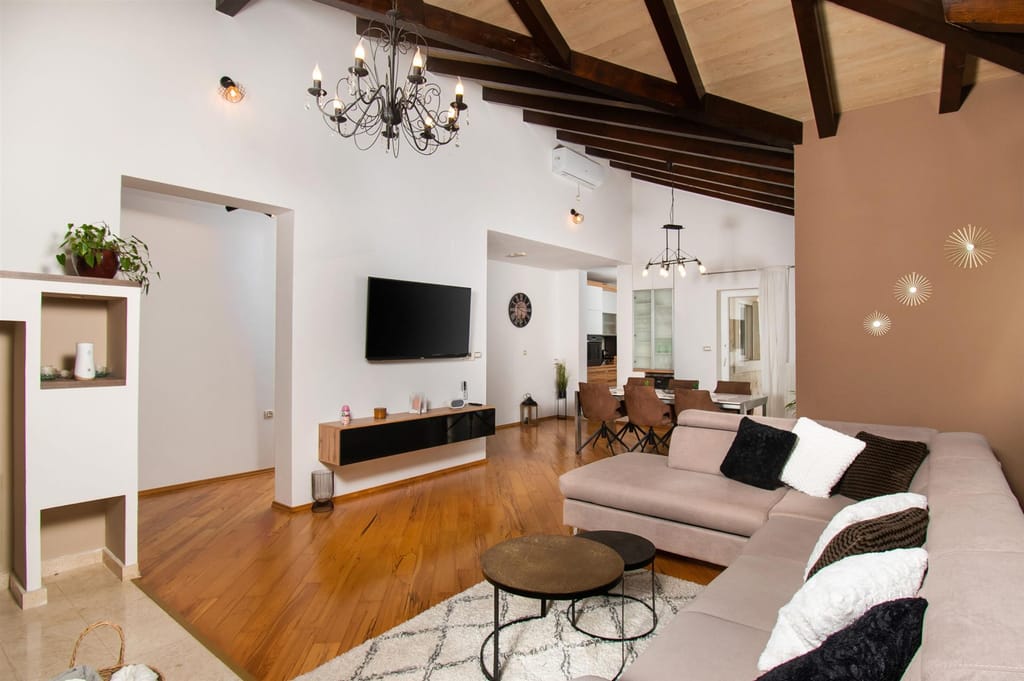 Living room with a corner sofa, a wall-mounted TV and the dining area beyond