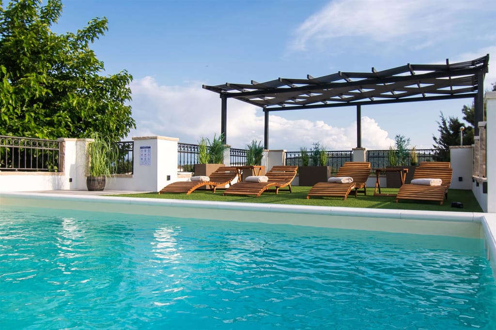 Pool with sunbeds under a wide blue sky