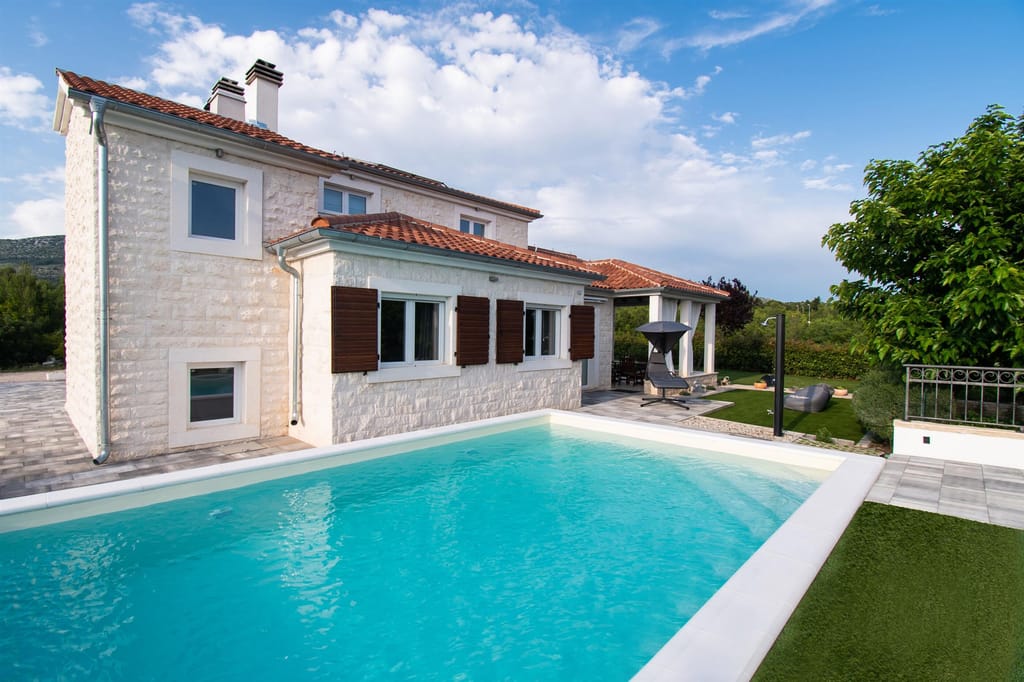 The stone villa and its turquoise pool on a clear summer day