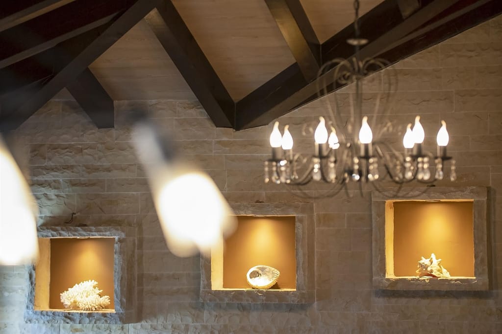 Lit niches in the white stone wall beneath dark wooden beams