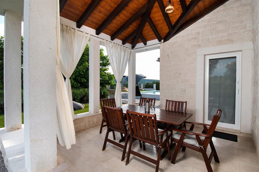 Covered terrace with a dining table and white curtains