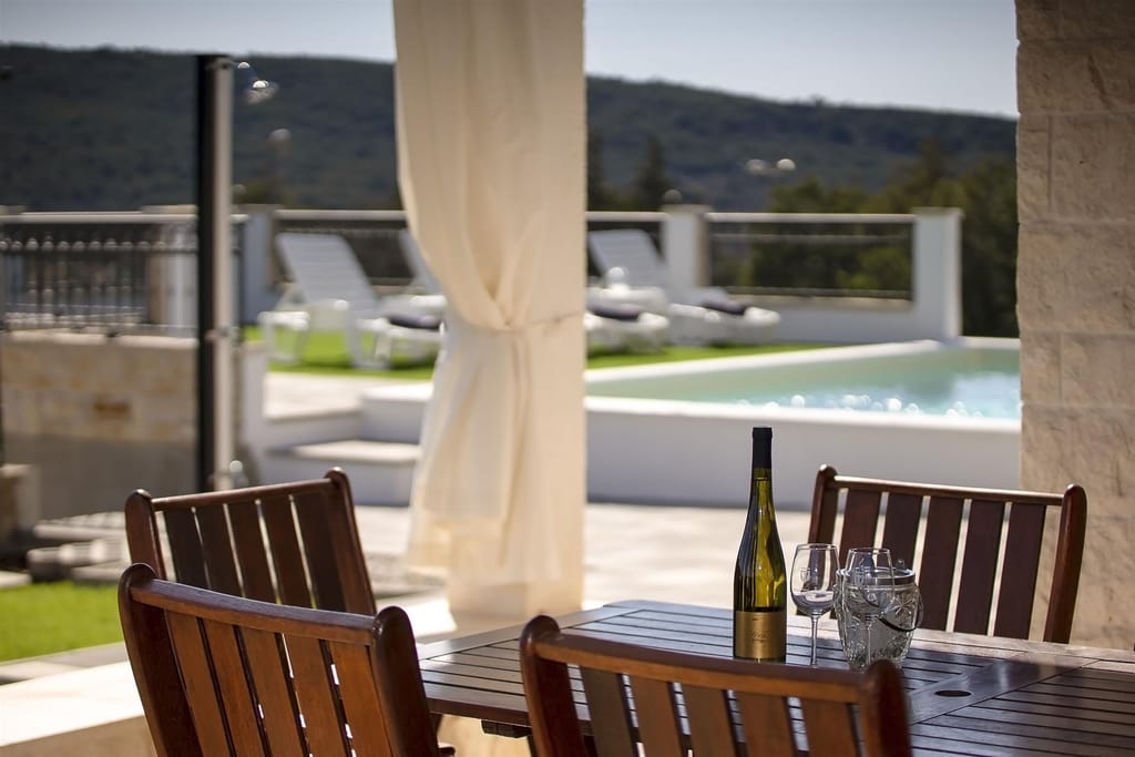 Terrace dining table with a bottle of wine and a view of the pool