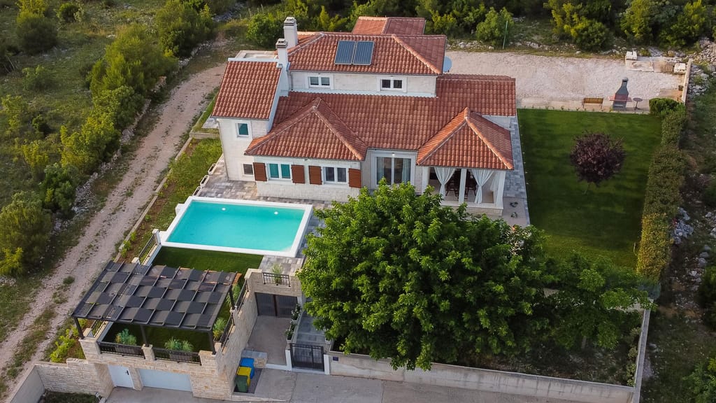 Aerial view of the villa, lawn and pool surrounded by pine trees