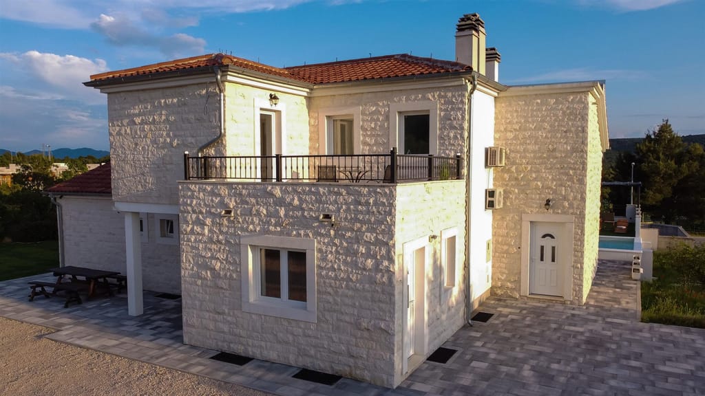 Stone villa with a first-floor balcony in the evening sun